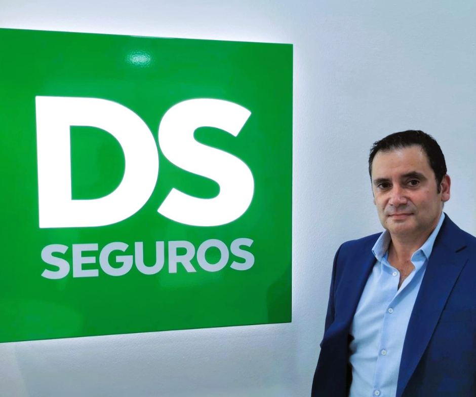 Retrato de Jorge Carvalho à frente da parede verde com o logótipo DS Seguros.